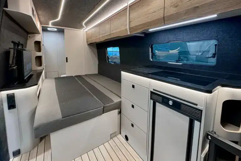 Innenraum des Rhön Camp The Seeker mit ausgezogenem Loungesofa, Küchenzeile und Oberschränken