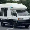 Weiß-schwarzer Toyota LiteAce Camper mit Hochdach und Allradantrieb auf einem Parkplatz