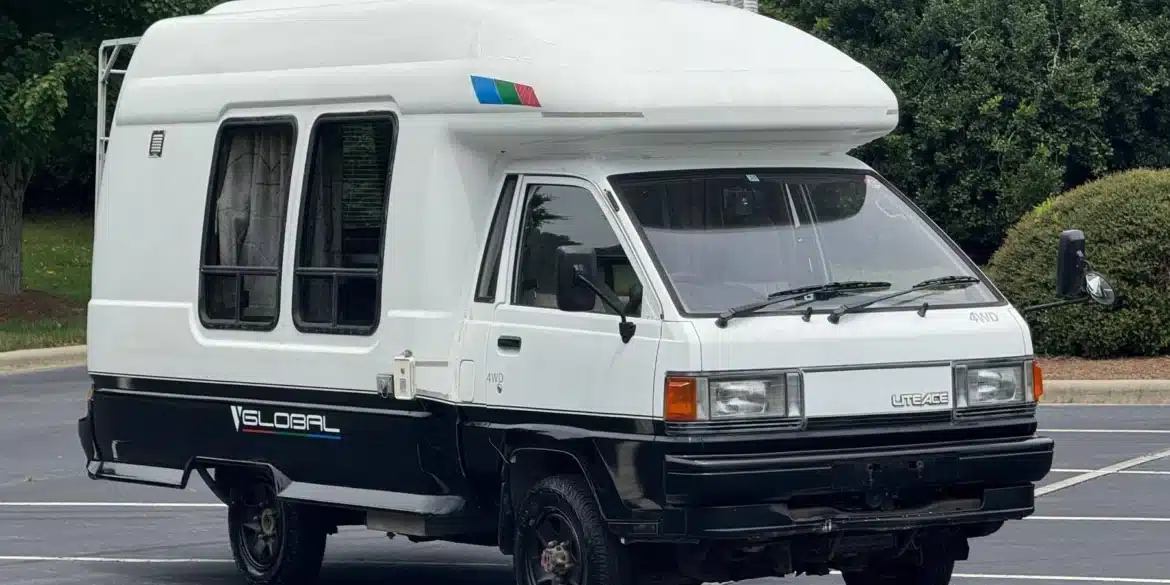 Weiß-schwarzer Toyota LiteAce Camper mit Hochdach und Allradantrieb auf einem Parkplatz