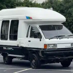 Weiß-schwarzer Toyota LiteAce Camper mit Hochdach und Allradantrieb auf einem Parkplatz