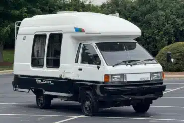Weiß-schwarzer Toyota LiteAce Camper mit Hochdach und Allradantrieb auf einem Parkplatz