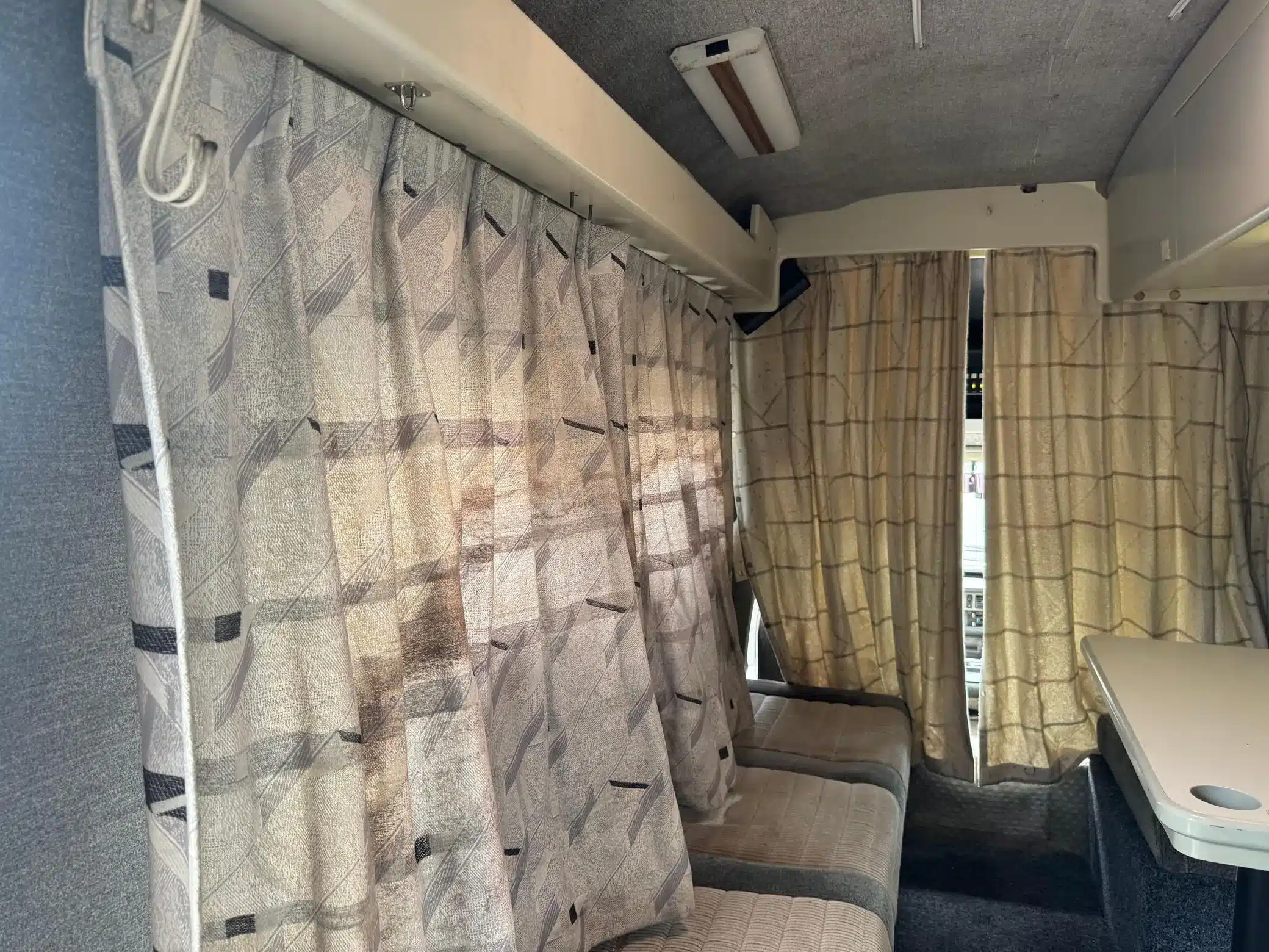Innenraum eines Toyota LiteAce Campers mit Sitzpolstern, Vorhängen und Tisch