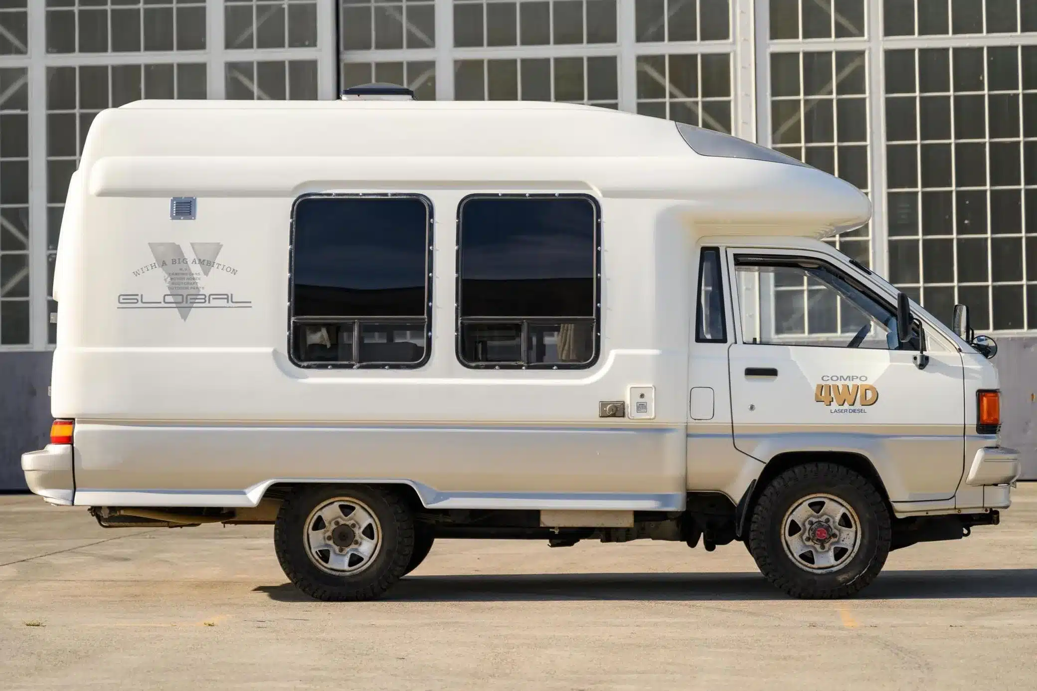Weißer Toyota TownAce Compo 4WD Camper in der Seitenansicht vor einem Gebäude