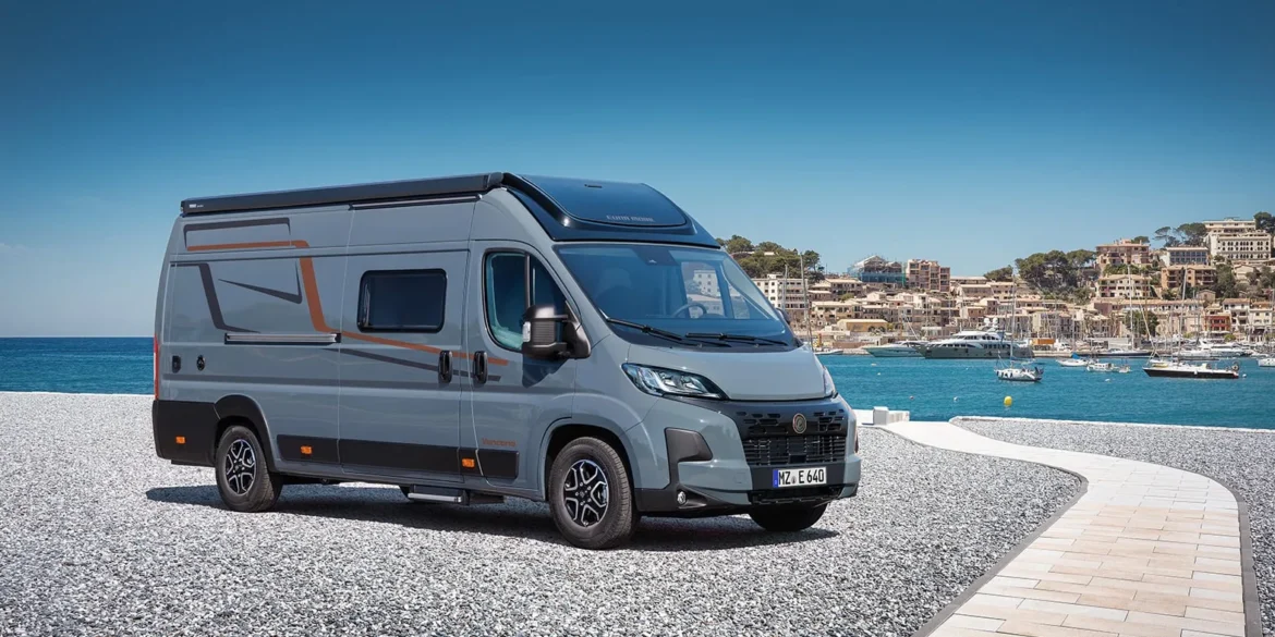 Grauer Vancona Campervan auf Fiat-Ducato-Basis vor einem Hafen mit Meer und Küstenstadt
