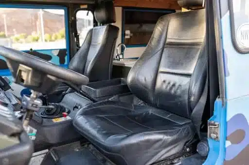 Innenraum eines blauen Volvo C303 TGB 1111 mit schwarzen Sitzen, Lenkrad und manueller Schaltung