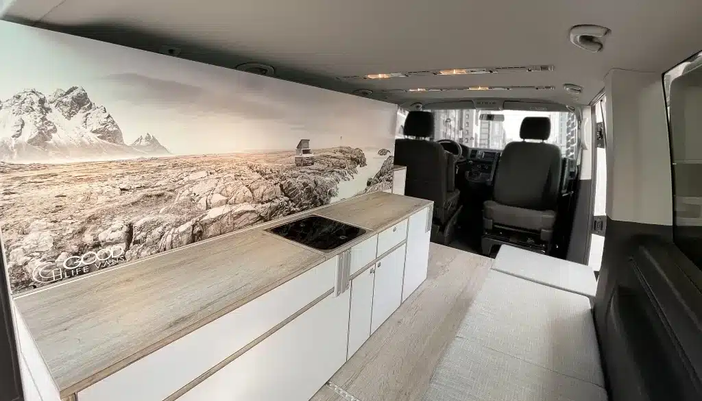 Innenraum eines VW T6 mit Küchenzeile, Kochfeld und Sitzbank des Camper Module ONE