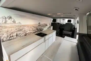 Innenraum eines VW T6 mit Küchenzeile, Kochfeld und Sitzbank des Camper Module ONE