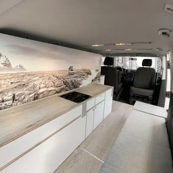Innenraum eines VW T6 mit Küchenzeile, Kochfeld und Sitzbank des Camper Module ONE