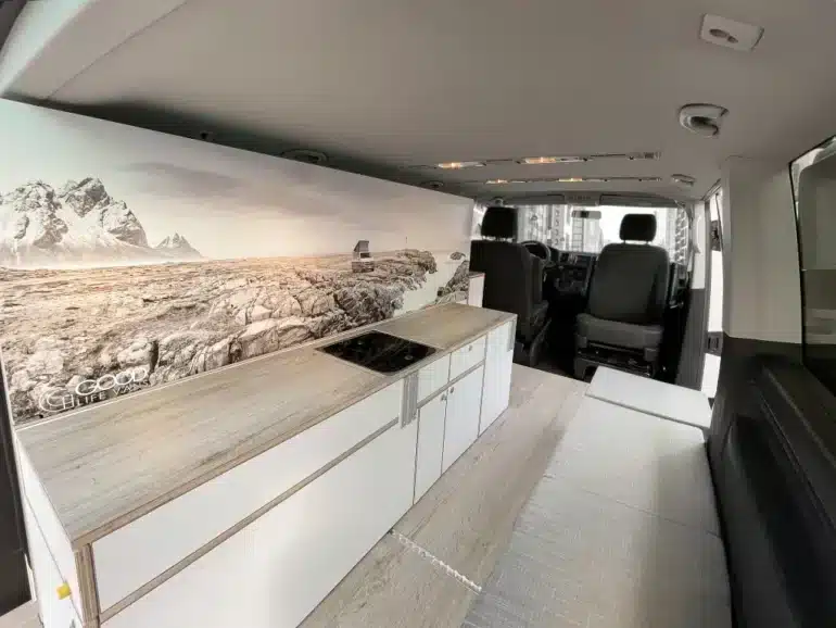 Innenraum eines VW T6 mit Küchenzeile, Kochfeld und Sitzbank des Camper Module ONE