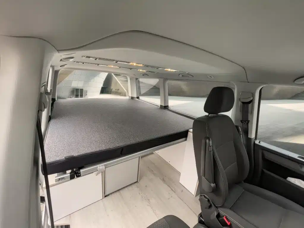 Innenraum eines VW T6 mit Camper Module ONE, Bettplattform, Stauraum und Vordersitzen