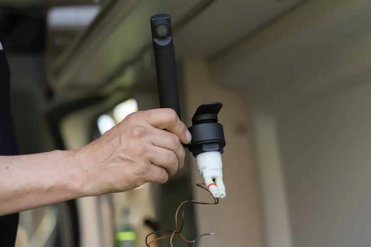 Hand hält eine schwarze Wohnmobil-Armatur mit Mikroschalter und Anschlusskabeln beim Einbau