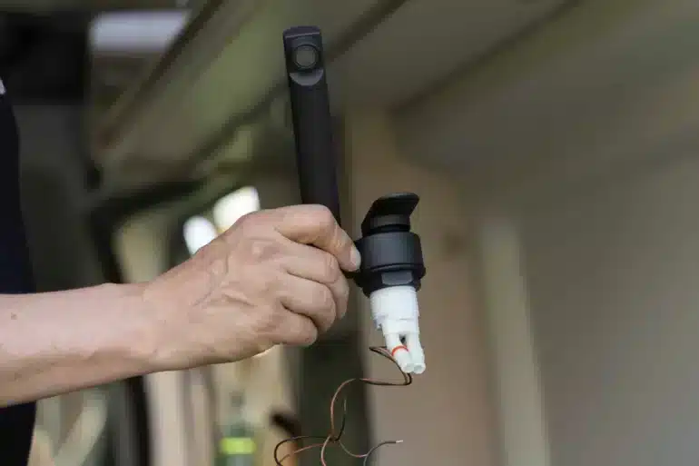 Hand hält eine schwarze Wohnmobil-Armatur mit Mikroschalter und Anschlusskabeln beim Einbau