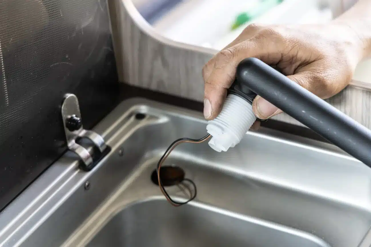 Hand montiert eine Wohnmobil-Armatur mit Wasseranschluss und Kabeln an einer Edelstahlspüle
