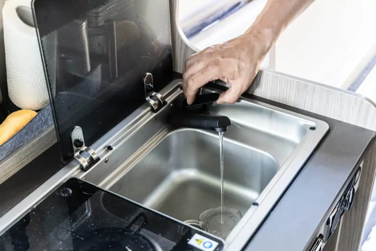 Schwarzer Wasserhahn in der Küchenspüle eines Campers mit laufendem Wasser