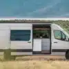Weißer VanCraft Waypoint XL Campervan mit geöffneter Seitentür in einer kargen Landschaft