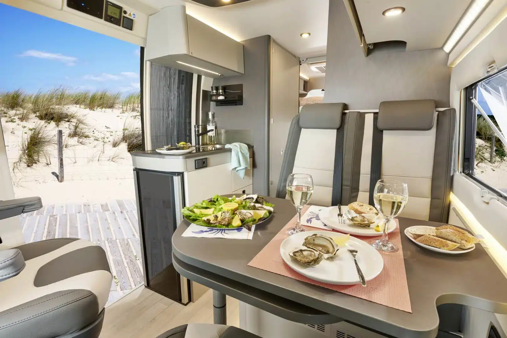 Innenraum eines Westfalia Nansen 600L mit Küche, Kühlschrank, Sitzgruppe und gedecktem Tisch