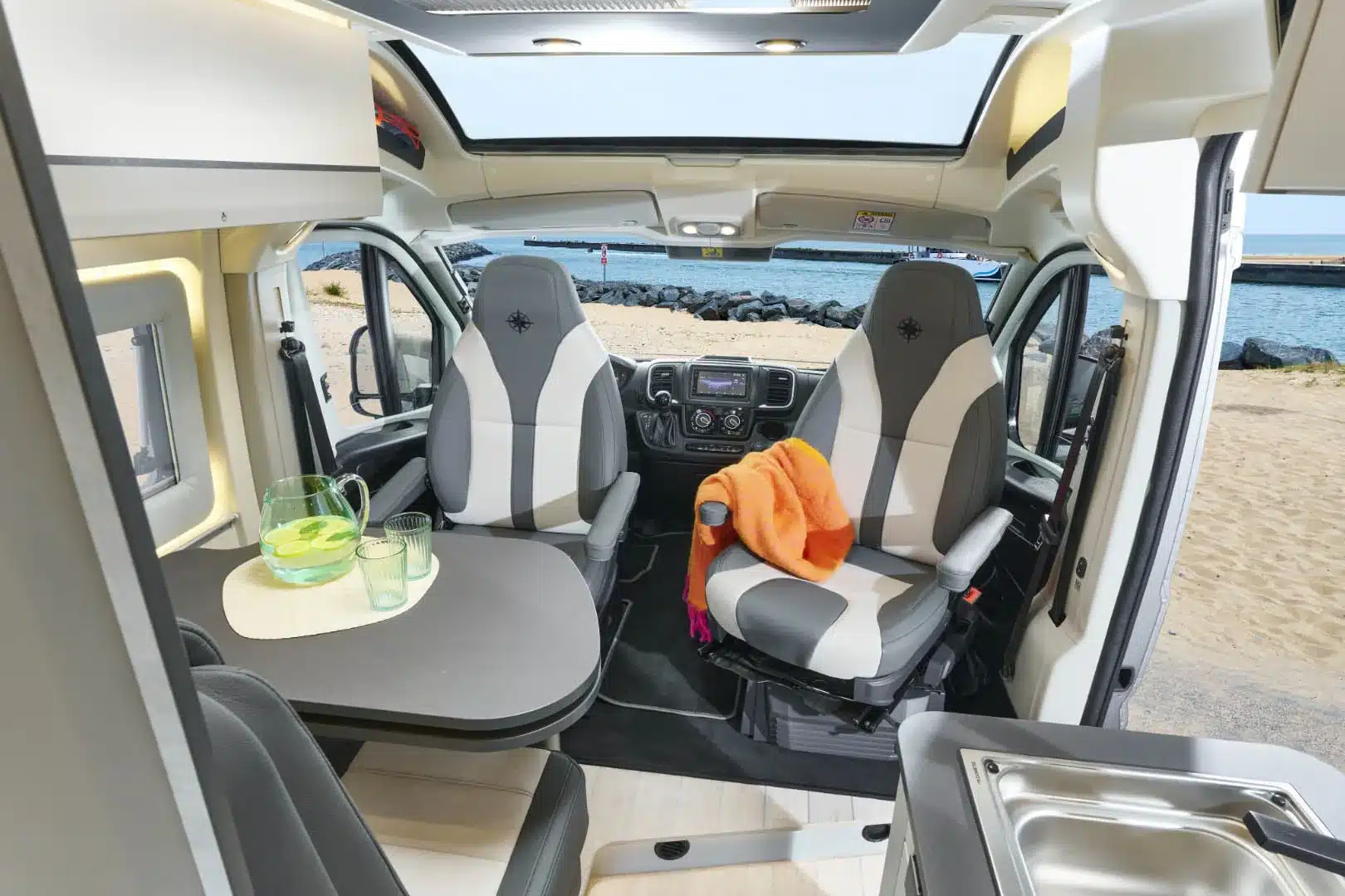 Innenraum des WESTFALIA Nansen 640LS mit Sitzgruppe, Küche und Fahrerhaus am Meer