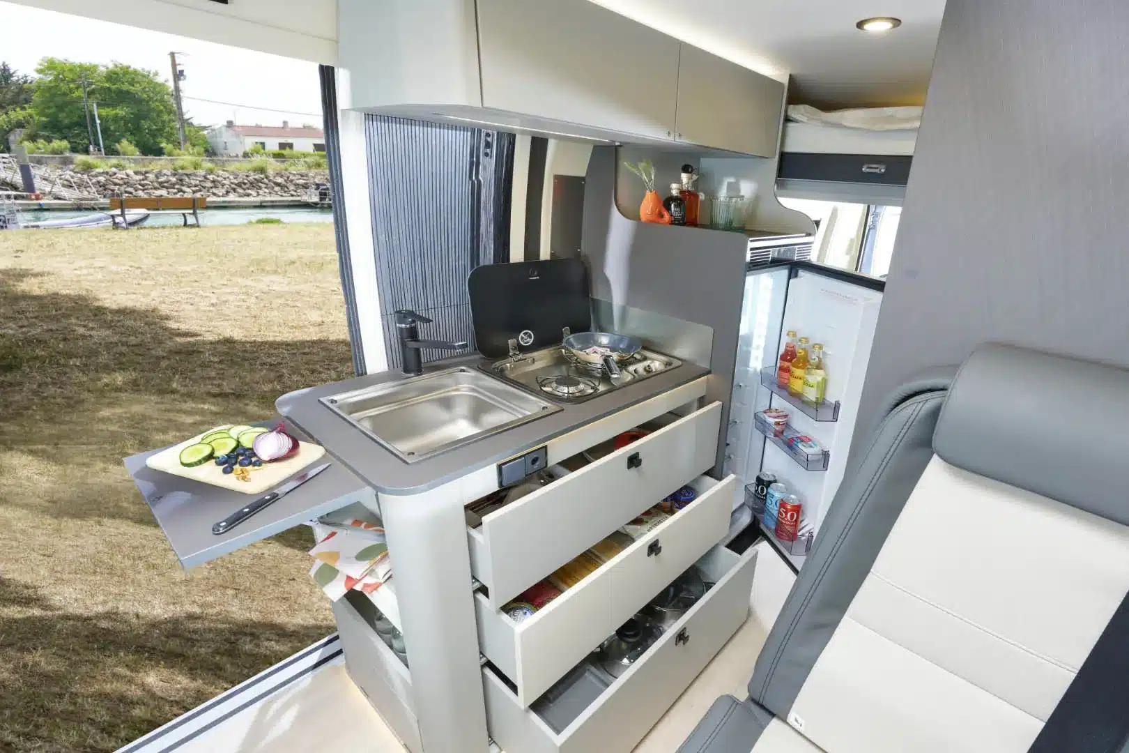 Innenraum eines WESTFALIA Nansen 640LS mit Küchenzeile, Spüle, Gaskocher, Schubladen und geöffnetem Kühlschrank