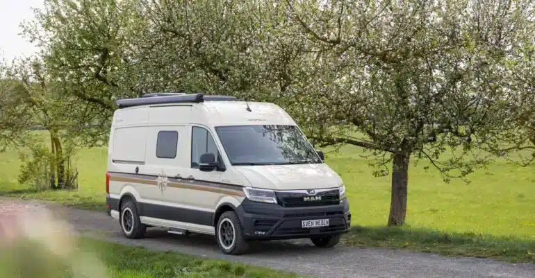 WESTFALIA Sven Hedin 50 Jahre Edition in heller Sonderlackierung auf einer Landstraße unter blühenden Bäumen
