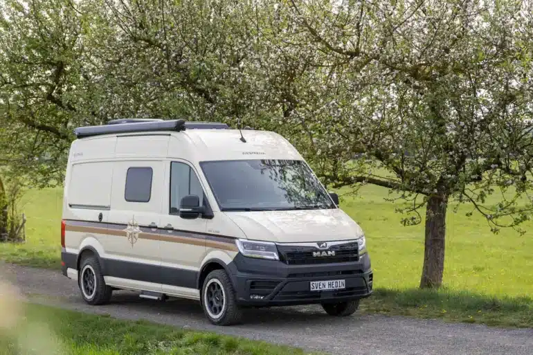 WESTFALIA Sven Hedin 50 Jahre Edition in heller Sonderlackierung auf einer Landstraße unter blühenden Bäumen