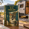 Rumänienkrimi „Wo die Straße endet“ auf einem Campingtisch, im Hintergrund ein Camper in der Natur