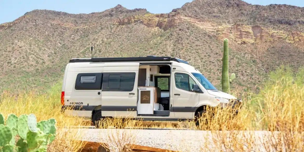 Weißer Papago Vans Zion Campervan mit geöffneter Schiebetür in einer trockenen Wüstenlandschaft