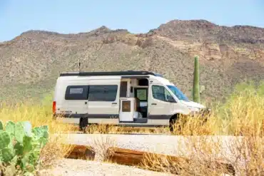Weißer Papago Vans Zion Campervan mit geöffneter Schiebetür in einer trockenen Wüstenlandschaft