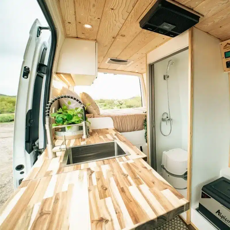 Innenraum des Papago Vans Zion mit Edelstahlspüle, Holzarbeitsfläche, Bett und Nassbad