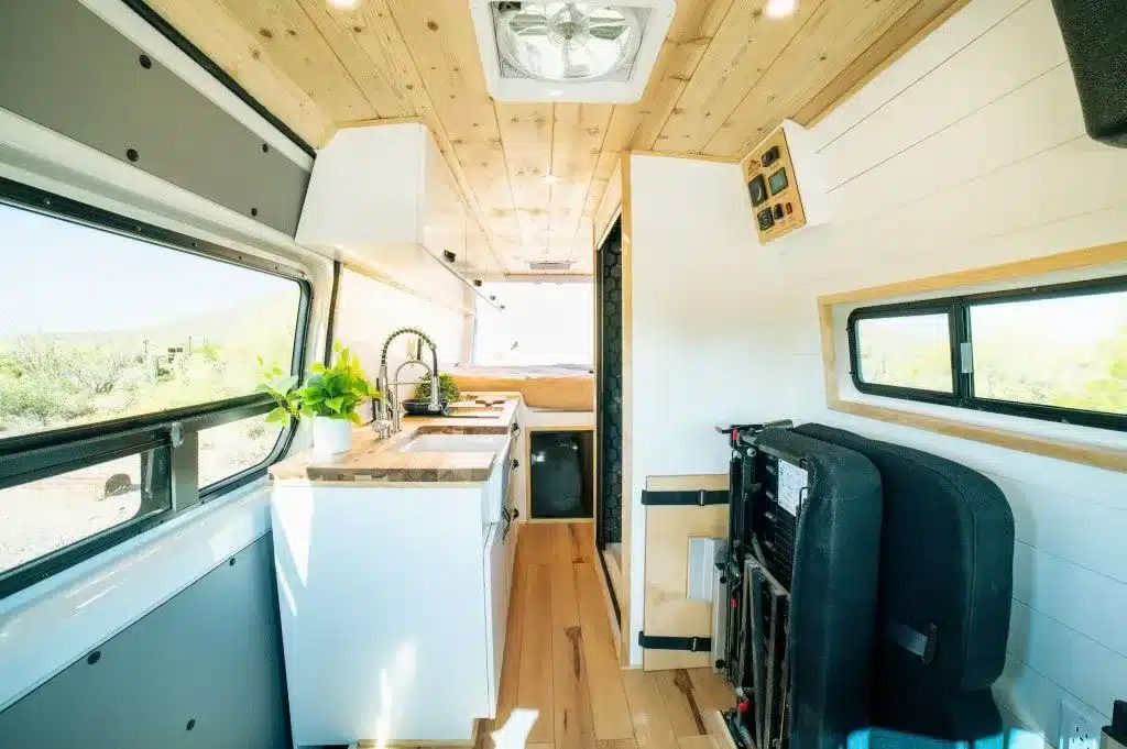 Heller Innenraum des Papago Vans Zion mit Küche, Holzdecke, Schlafbereich und Sitzbank