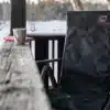 Schwarze beheizbare Seat Cover Stuhlauflage von Outchair auf einem Klappstuhl im Schnee