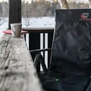 Schwarze beheizbare Seat Cover Stuhlauflage von Outchair auf einem Klappstuhl im Schnee