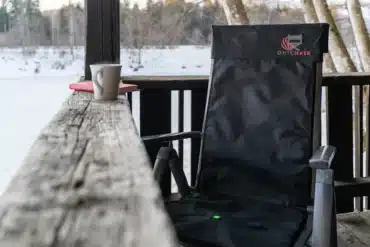 Schwarze beheizbare Seat Cover Stuhlauflage von Outchair auf einem Klappstuhl im Schnee